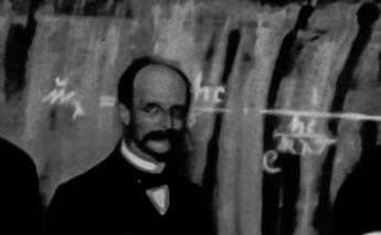 Max Planck, 1911, im Hintergrund das Plancksche Strahlungsgesetz. Deren Herleitung gilt als die Geburtsstunde der Quantenphysik.